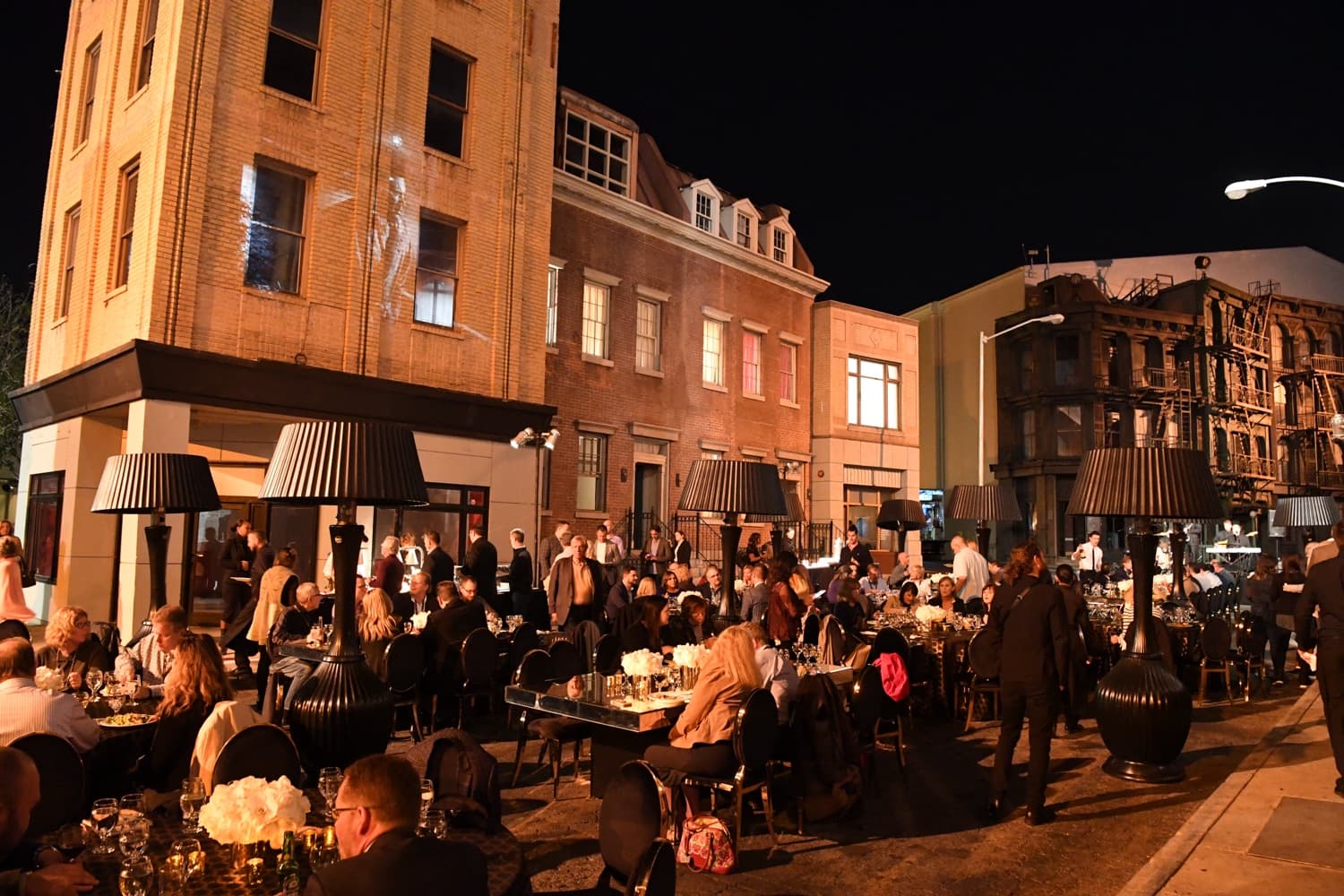 Guests at an outdoor evening gala dinner under warm light